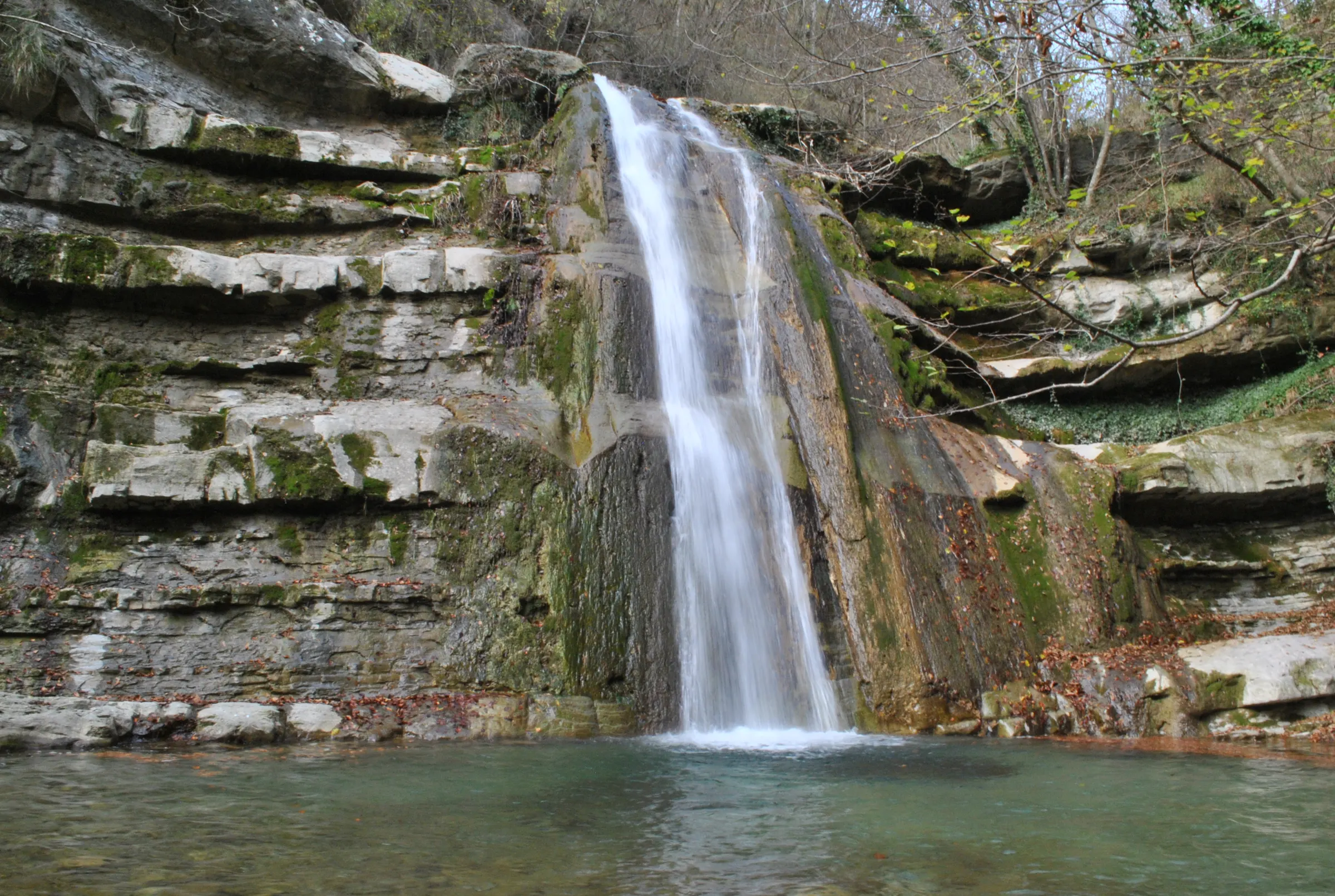 Un salto d'acqua lungo il torrente Acquacheta, con una pozza verde alla base