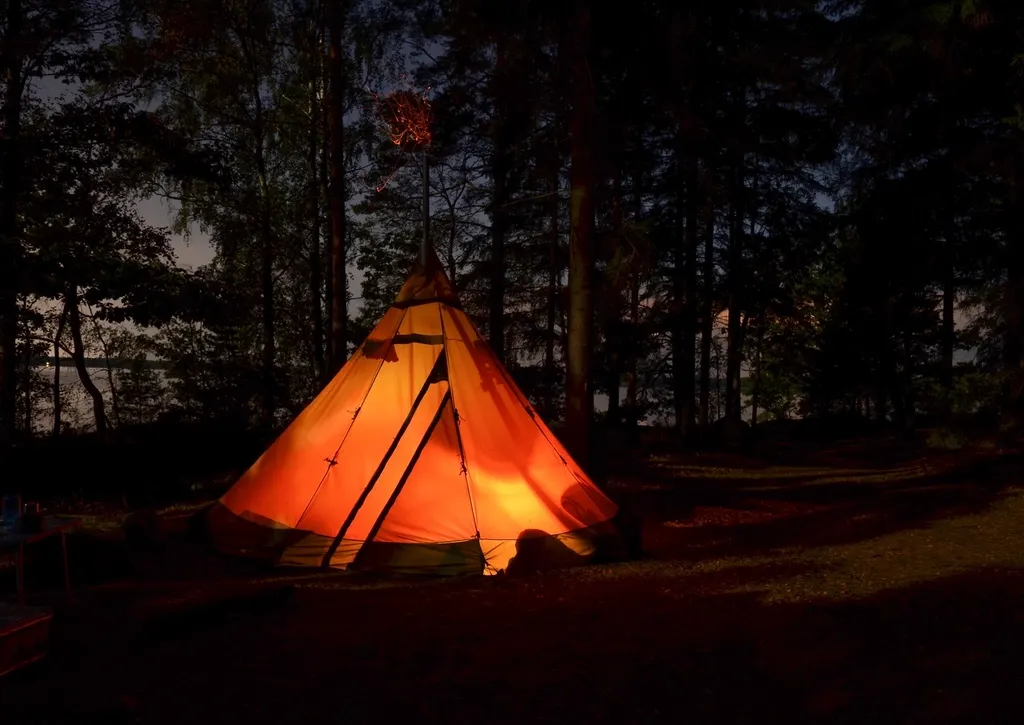 Una tenda illuminata di sera in mezzo al bosco